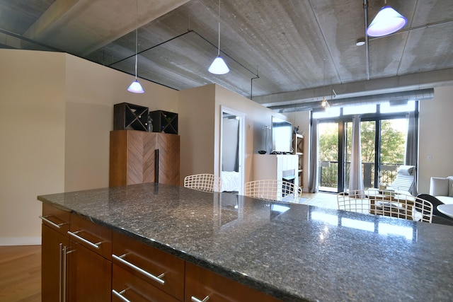 kitchen featuring dark stone counters, pendant lighting, and light wood-type flooring