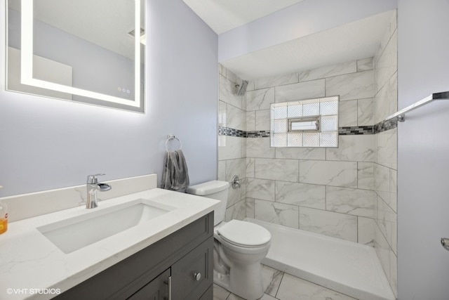 bathroom featuring vanity, toilet, and tiled shower