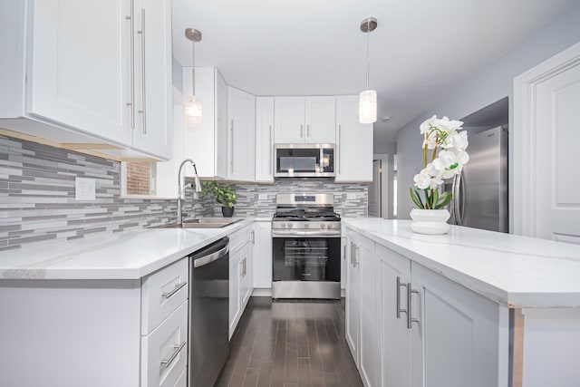 kitchen with stainless steel appliances, sink, dark hardwood / wood-style floors, white cabinetry, and decorative light fixtures