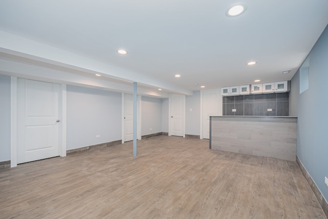 basement featuring light hardwood / wood-style floors and bar