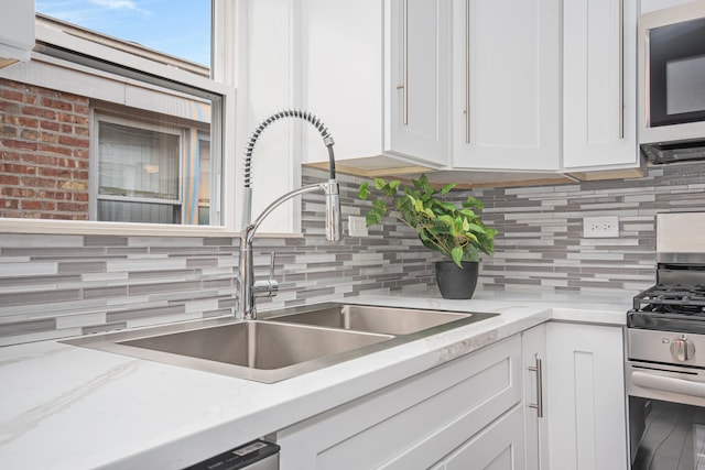 kitchen featuring white cabinets, appliances with stainless steel finishes, sink, and tasteful backsplash