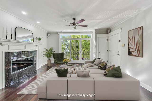 living room with dark wood-type flooring, a premium fireplace, ceiling fan, and crown molding