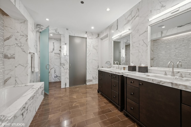 bathroom featuring vanity, independent shower and bath, and tile walls