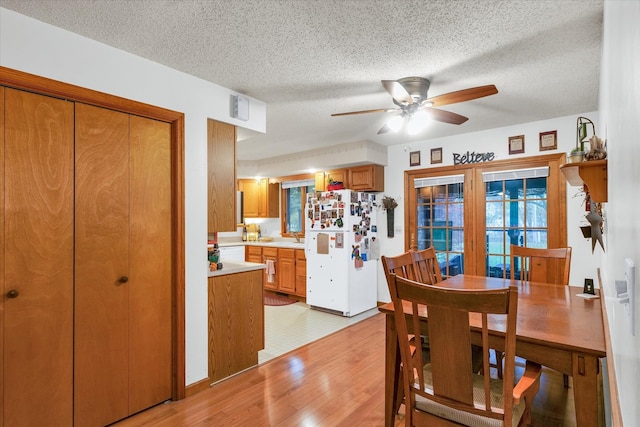 dining area featuring a textured ceiling, ceiling fan, and light hardwood / wood-style flooring