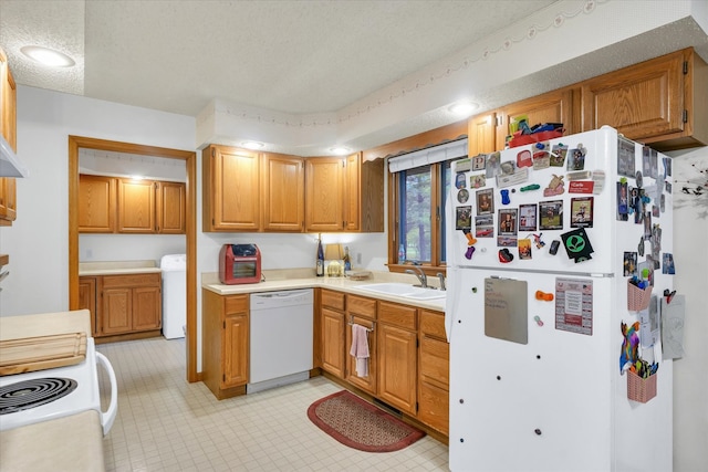 kitchen featuring white appliances, washer / dryer, a textured ceiling, and sink