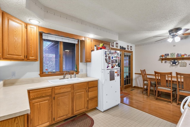 kitchen featuring white refrigerator, a textured ceiling, sink, ceiling fan, and light hardwood / wood-style flooring