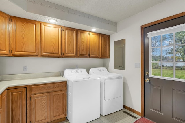 laundry area with electric panel, cabinets, a textured ceiling, and washer and dryer