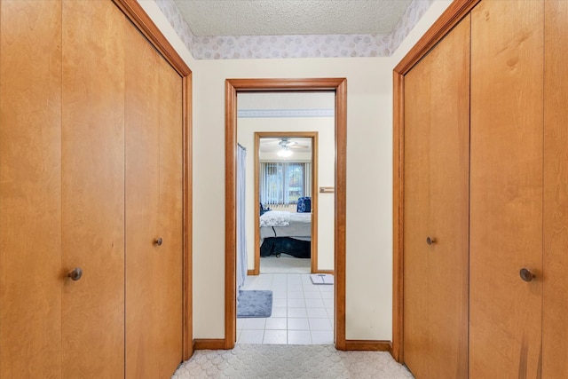 hallway featuring a textured ceiling and light tile patterned flooring