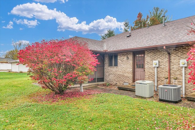 back of property featuring central AC unit and a yard