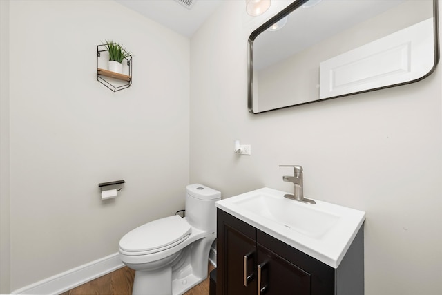 bathroom featuring toilet, vanity, and hardwood / wood-style floors