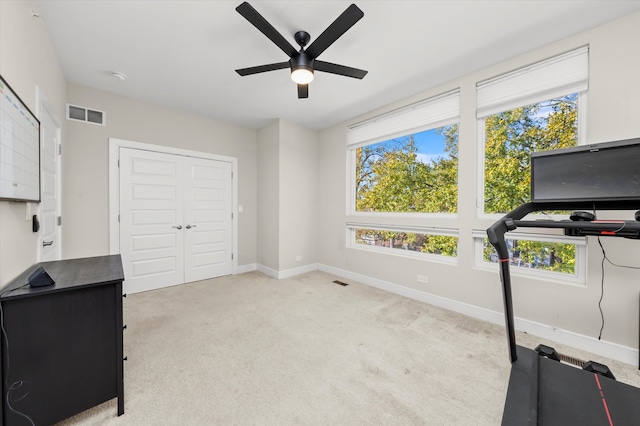 exercise area featuring light colored carpet and ceiling fan