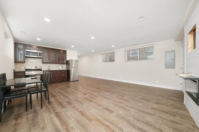 kitchen with electric panel, appliances with stainless steel finishes, dark brown cabinetry, and light hardwood / wood-style flooring