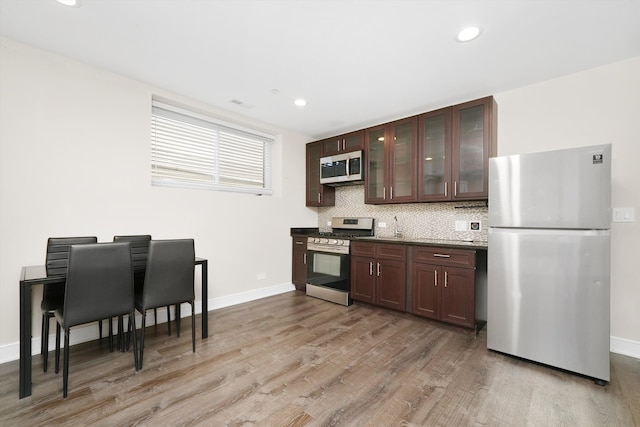 kitchen with stainless steel appliances, light hardwood / wood-style floors, dark brown cabinets, and decorative backsplash