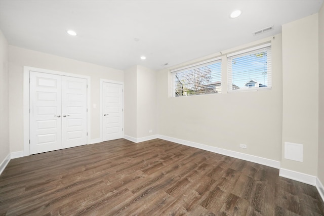 unfurnished bedroom featuring dark wood-type flooring and two closets