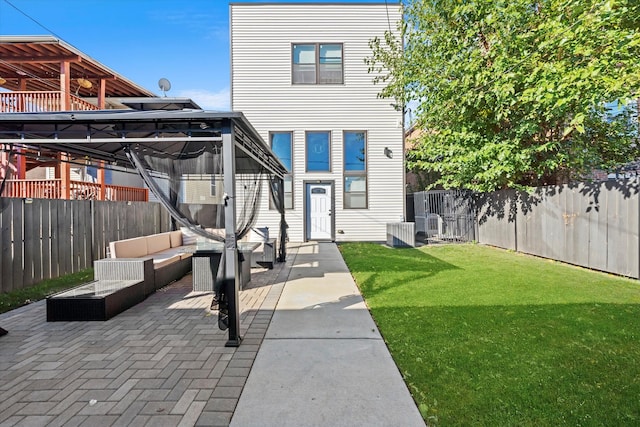 back of house with an outdoor living space, a patio area, and a lawn