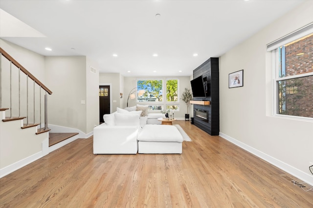 living room with a fireplace and light wood-type flooring