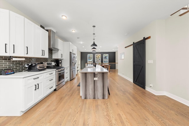 kitchen with decorative light fixtures, white cabinetry, a kitchen island with sink, and stainless steel appliances