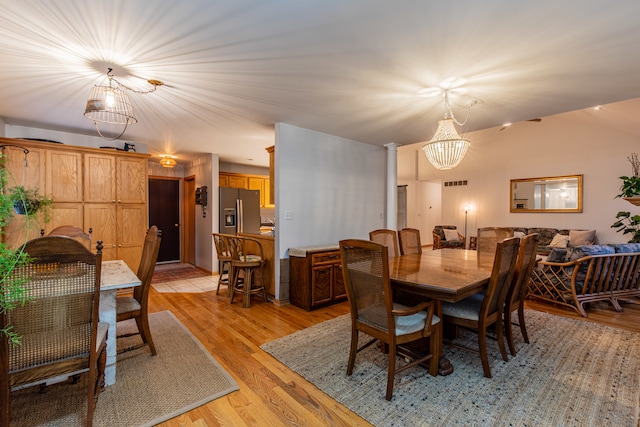 dining area with a notable chandelier, light wood-type flooring, and ornate columns