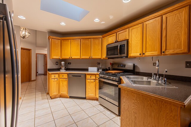 kitchen with a skylight, sink, light tile patterned flooring, and stainless steel appliances