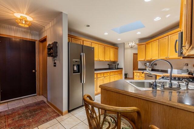 kitchen featuring sink, light tile patterned floors, stainless steel appliances, and a skylight