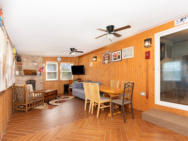 dining room with a fireplace, parquet flooring, wooden walls, and ceiling fan