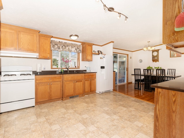 kitchen with ornamental molding, a notable chandelier, sink, and white appliances