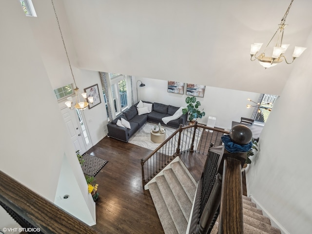 staircase featuring a towering ceiling, hardwood / wood-style flooring, and a chandelier