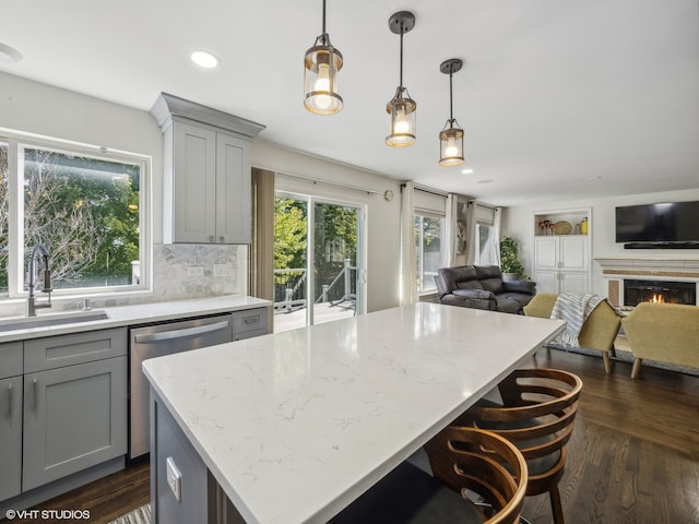 kitchen featuring sink, hanging light fixtures, dark hardwood / wood-style flooring, a center island, and decorative backsplash