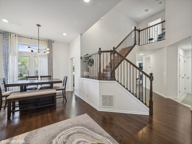 dining area with a high ceiling, a notable chandelier, and dark hardwood / wood-style floors