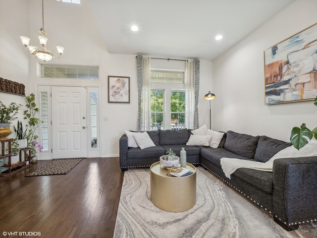 living room with a towering ceiling, an inviting chandelier, and dark hardwood / wood-style flooring