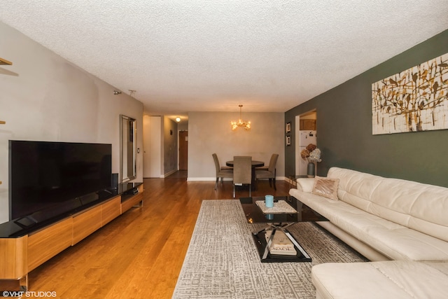 living room with hardwood / wood-style floors, a textured ceiling, and a notable chandelier