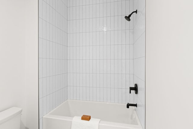 bathroom featuring tiled shower / bath combo and toilet