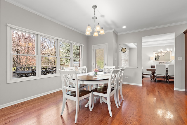 dining area with an inviting chandelier, ornamental molding, and wood-type flooring