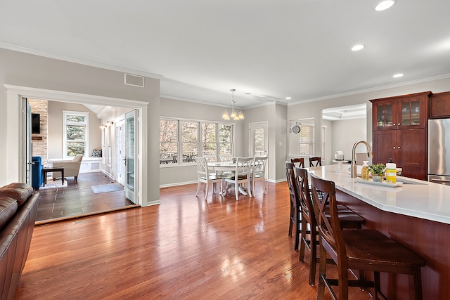 dining area with sink, an inviting chandelier, hardwood / wood-style flooring, and ornamental molding