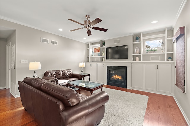 living room featuring hardwood / wood-style floors, ceiling fan, and ornamental molding