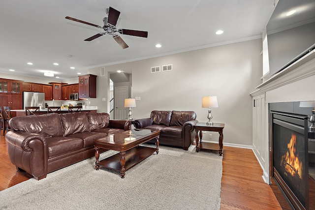 living room featuring ceiling fan, light hardwood / wood-style flooring, and ornamental molding