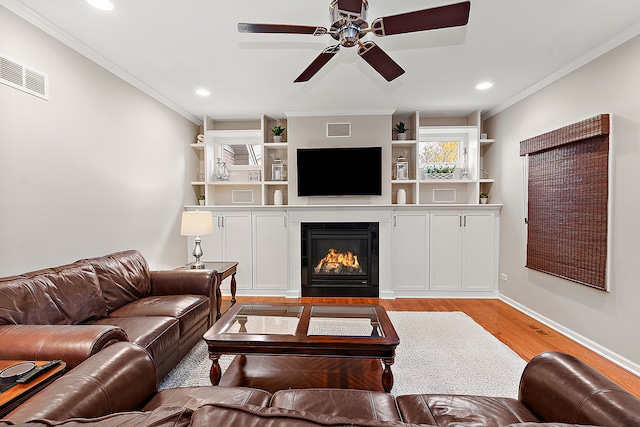 living room with light wood-type flooring, ceiling fan, and crown molding