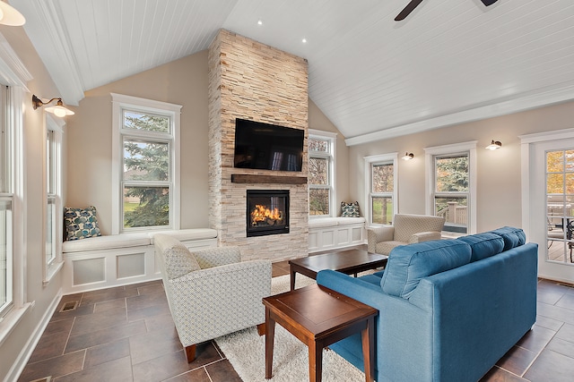 living room with a stone fireplace, a healthy amount of sunlight, and vaulted ceiling