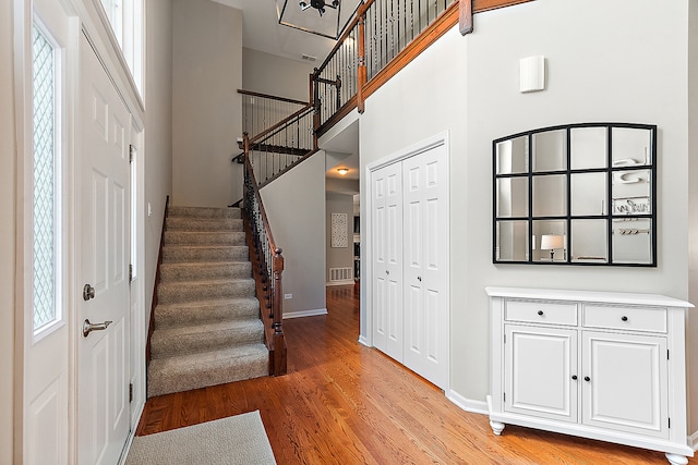 foyer featuring a towering ceiling and light hardwood / wood-style flooring