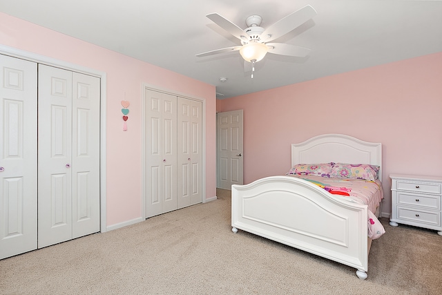 bedroom featuring carpet flooring, ceiling fan, and two closets