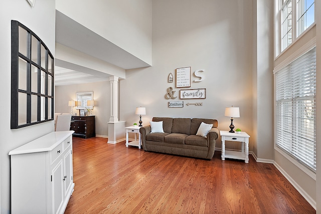 living room with decorative columns, hardwood / wood-style flooring, and a towering ceiling