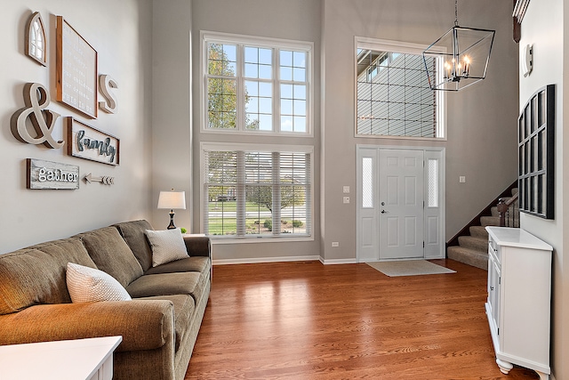 entrance foyer with an inviting chandelier, hardwood / wood-style floors, and a towering ceiling