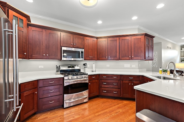 kitchen with light hardwood / wood-style floors, kitchen peninsula, sink, ornamental molding, and appliances with stainless steel finishes