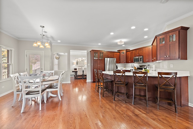 kitchen with stainless steel appliances, light hardwood / wood-style floors, a notable chandelier, crown molding, and decorative light fixtures