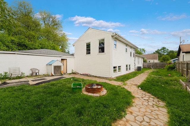 rear view of house featuring central AC, a lawn, and a fire pit