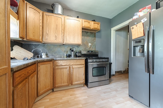 kitchen featuring light wood-type flooring, appliances with stainless steel finishes, and decorative backsplash