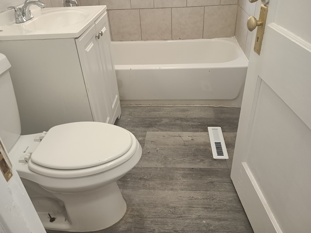 bathroom featuring vanity, a tub to relax in, and toilet