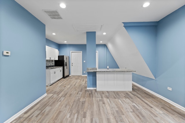 kitchen with white cabinets, stainless steel refrigerator with ice dispenser, light wood-type flooring, and a breakfast bar