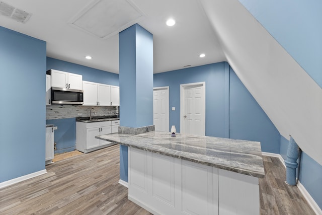 kitchen featuring dark stone countertops, tasteful backsplash, light wood-type flooring, and white cabinets