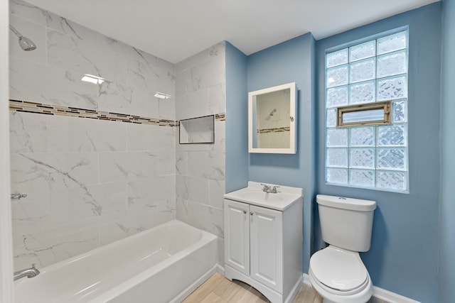 full bathroom featuring vanity, hardwood / wood-style flooring, tiled shower / bath, and toilet